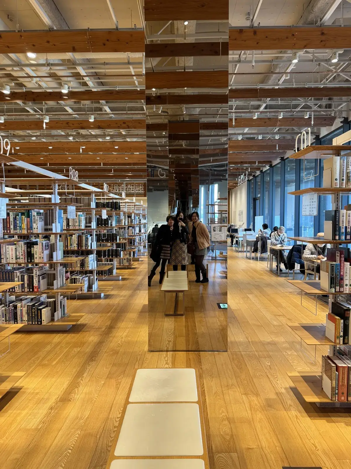 富山市立圖書館 鏡面柱書架 — 鏡柱倒影與書架無限延伸空間感