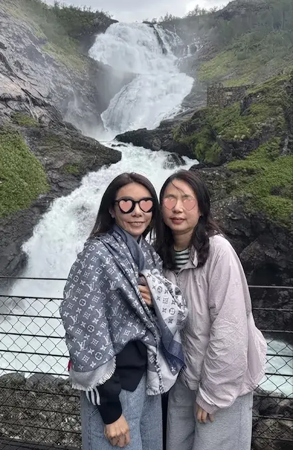 瀑布前合照原始照片 右側女士額頭有幾根被風吹亂貼在臉上的頭髮 眼睛處已加愛心貼紙保護隱私