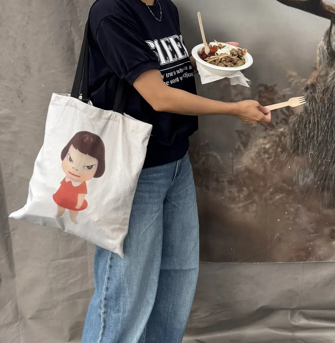 奈良美智 Missing in Action 托特包實穿,肩背搭配深藍上衣與牛仔褲,倫敦市集街拍